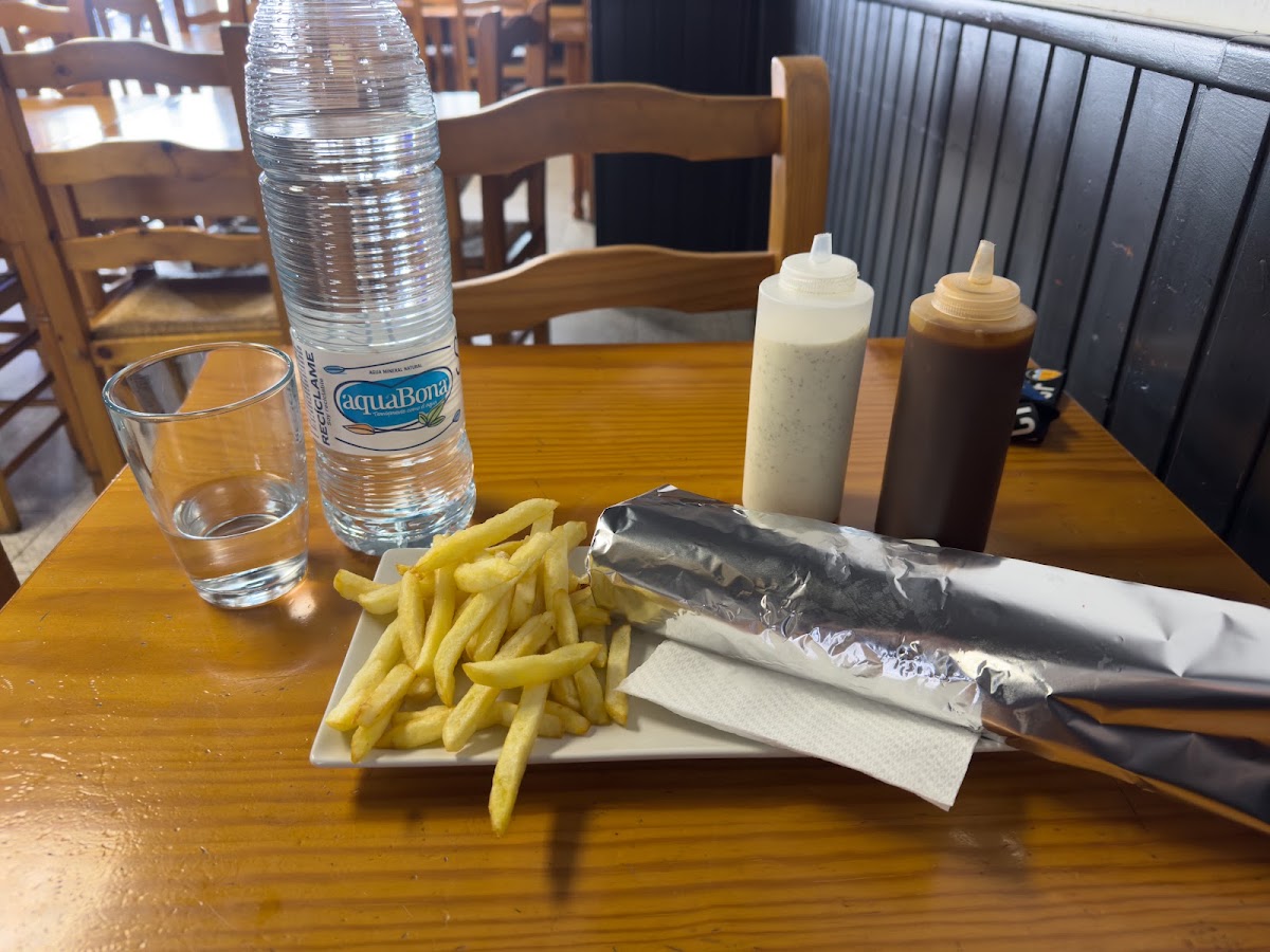Kebab con patatas y botella de agua en la mesa