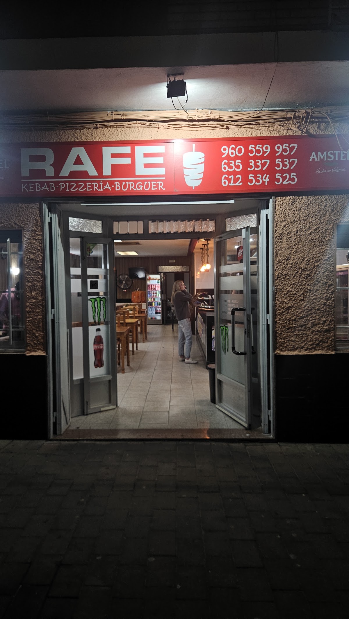 Entrada del local Rafe pizza kebab de noche, con el rótulo rojo iluminado